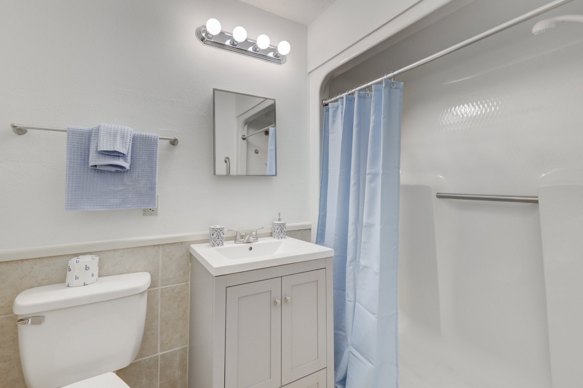 A clean, modern bathroom with a white sink and a blue shower curtain.