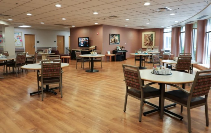 An empty dining area with neatly arranged tables and chairs on a wooden floor.