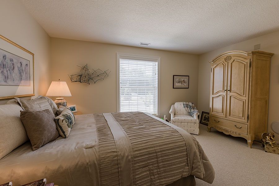 Cozy bedroom with a large bed, armchair, and soft lighting.