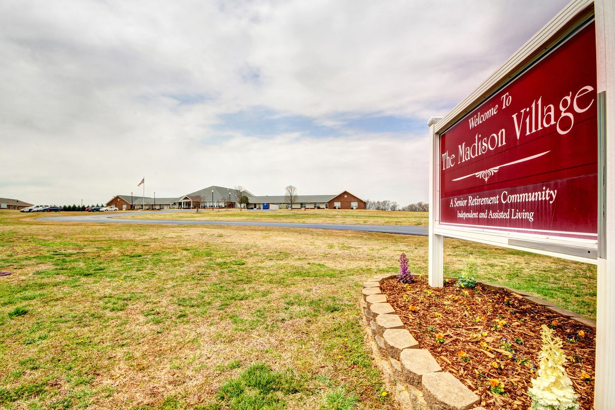 An outdoor view of a school with a sign in the foreground.