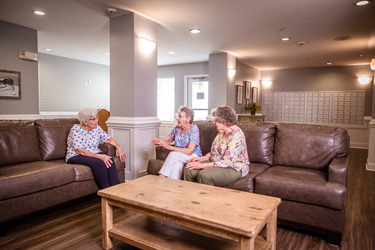 A group of seniors having a conversation in a cozy living room setting.