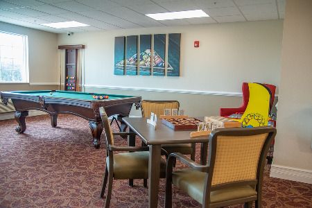 A cozy game room featuring a pool table, a chess board on a table, and comfortable seating arrangements.