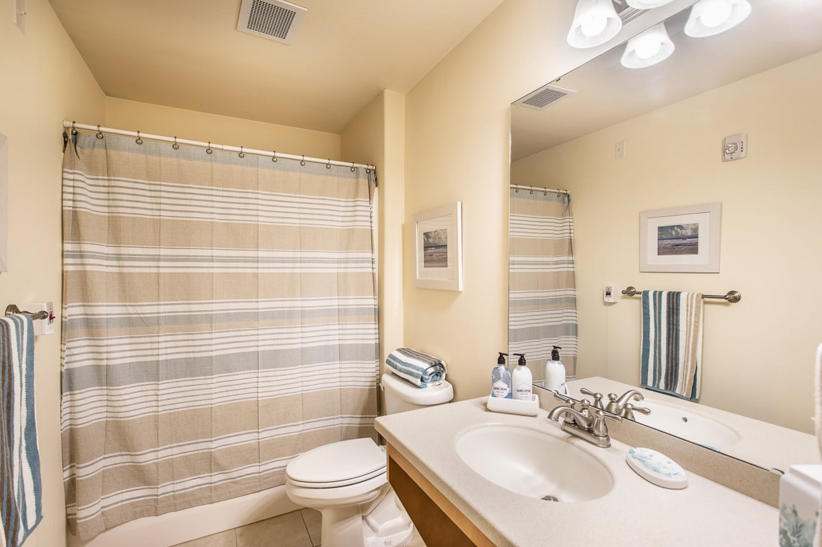 A clean and bright bathroom with modern fixtures, including a sink, toilet, and a striped shower curtain.