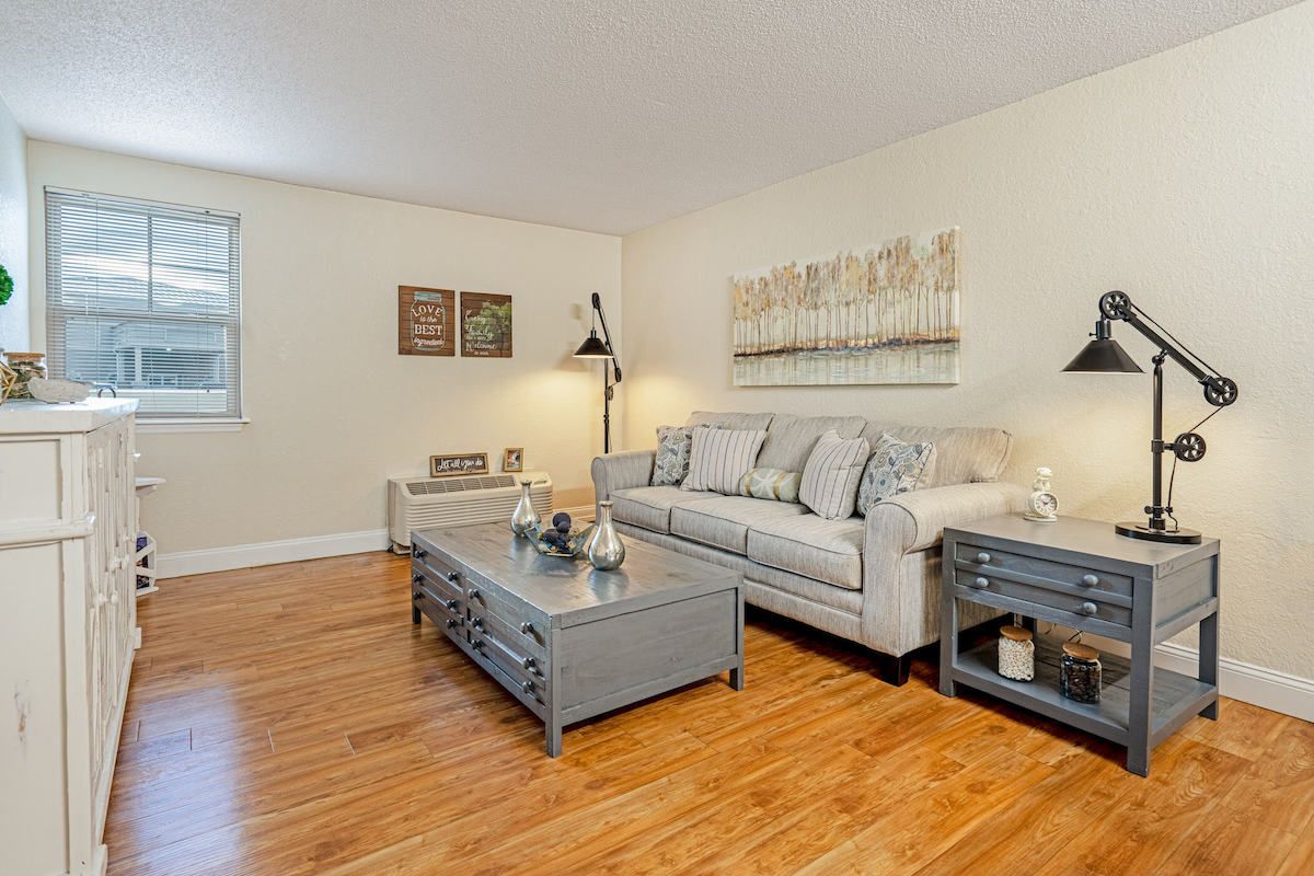 A cozy living room with a comfortable sofa, coffee table, and stylish lamps on hardwood floors.