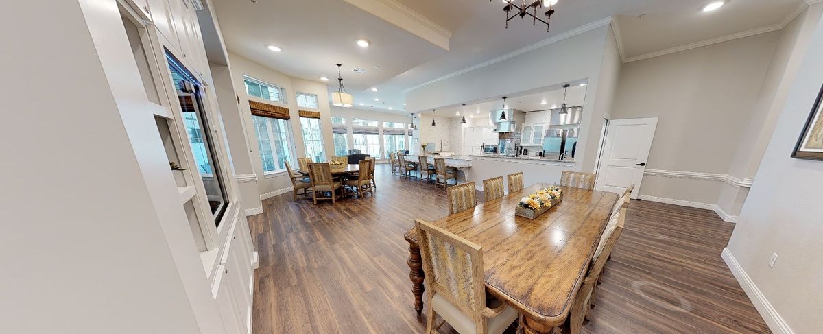 A spacious open-plan dining and kitchen area featuring wooden furniture and modern lighting.