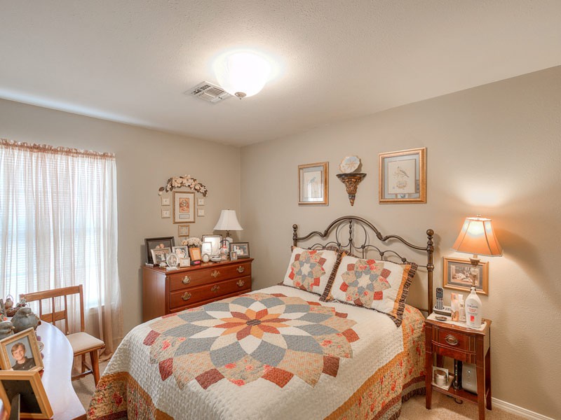 A cozy bedroom with a colorful quilt on the bed, wooden furniture, and tasteful decor.