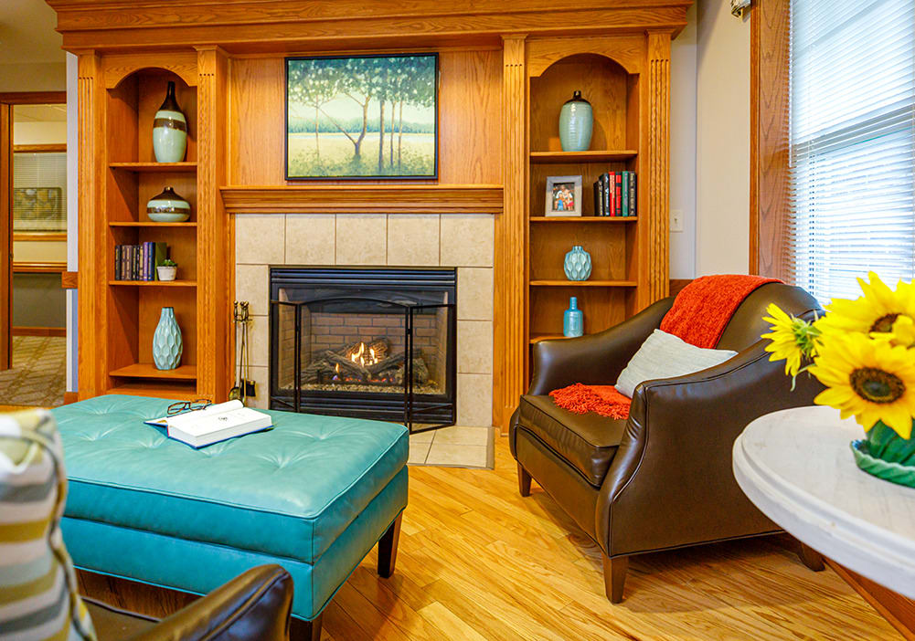 A cozy living room with a fireplace, armchair, and decorative shelves.