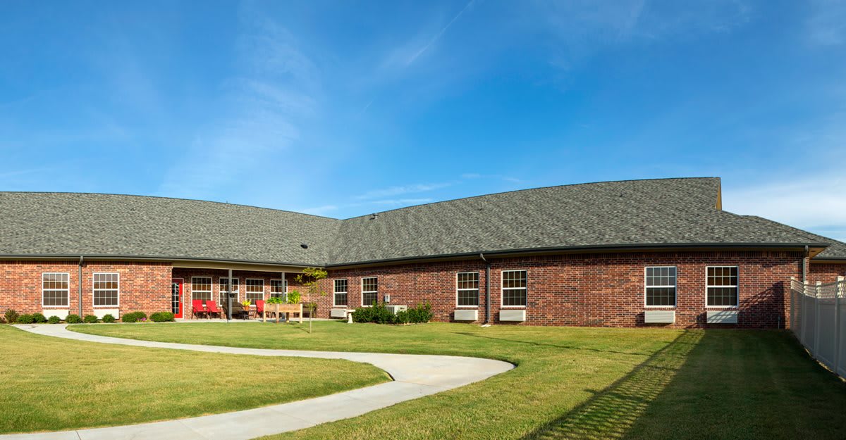 A brick building with a well-maintained lawn under a clear blue sky.