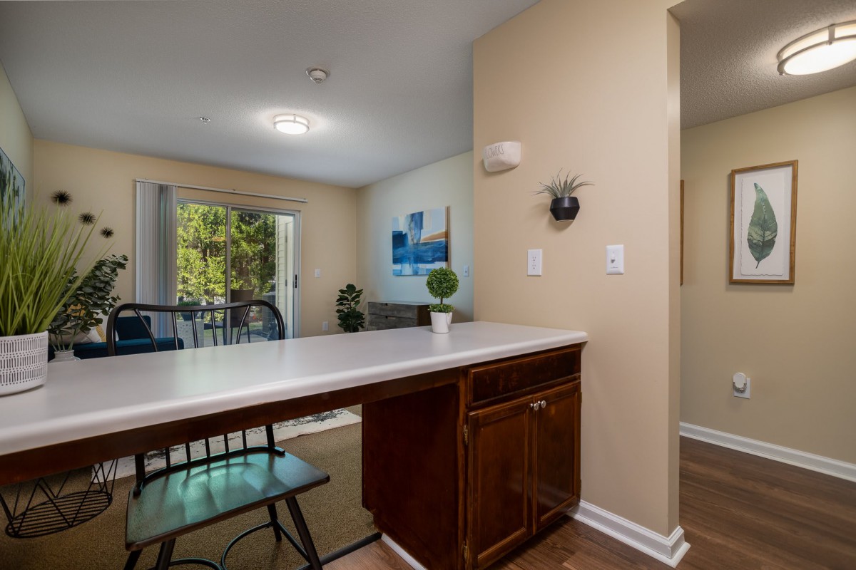 A cozy dining area with a countertop and chairs, featuring plants and wall art for decor.