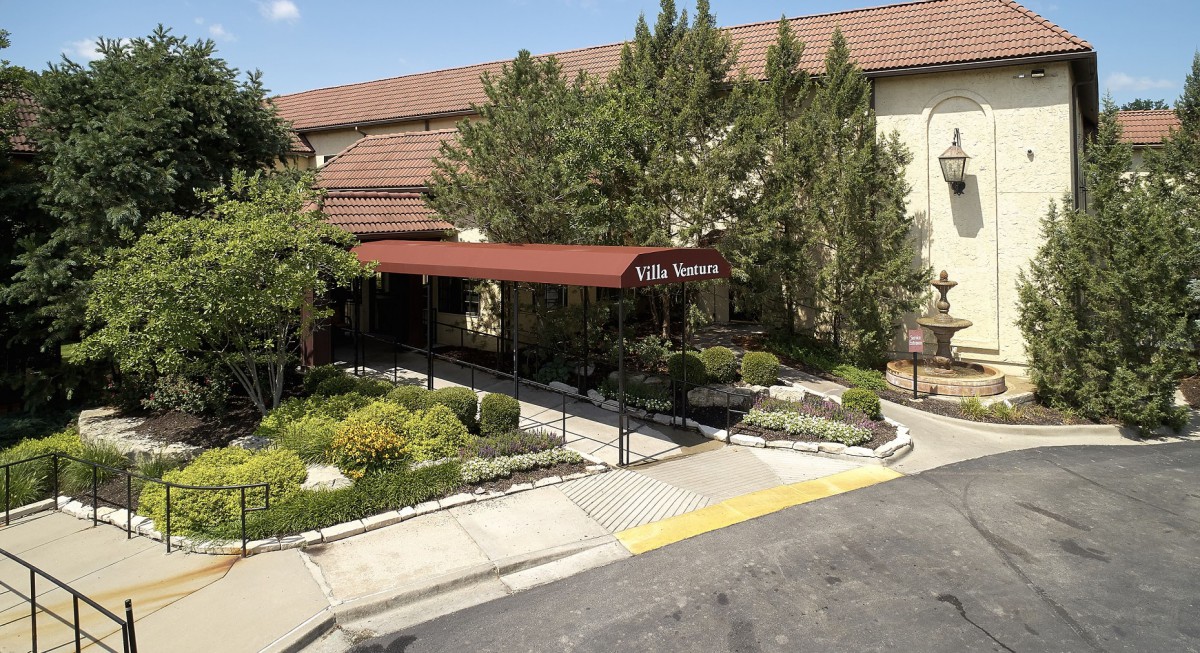 A building entrance with a red canopy and landscaped surroundings.