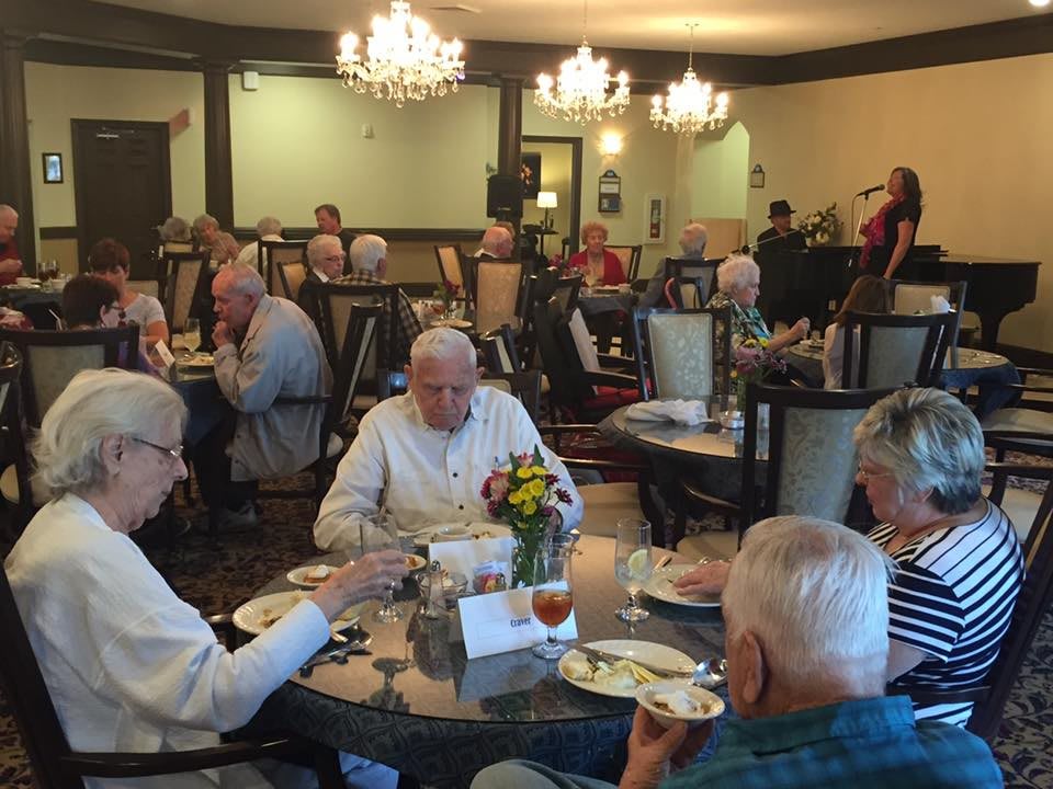 Seniors enjoying a meal together in a warmly lit dining area.