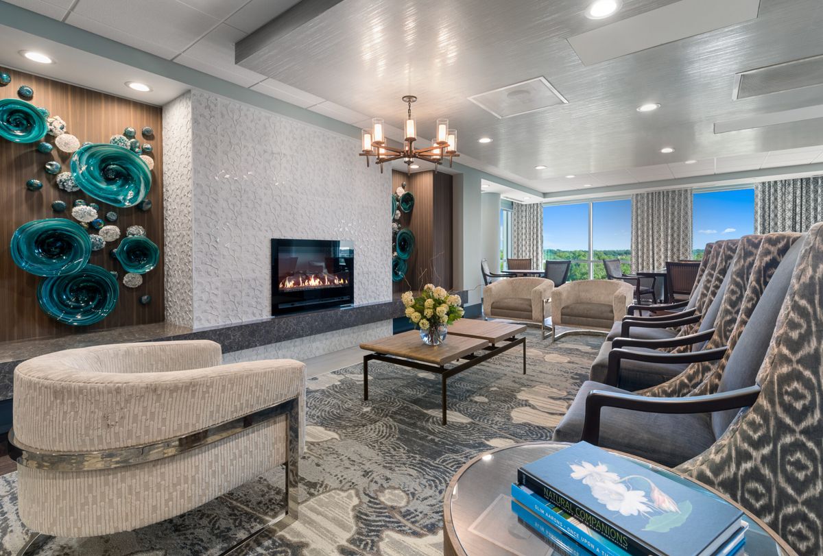 A modern living room with elegant decor, featuring a fireplace, chandelier, and comfortable seating.