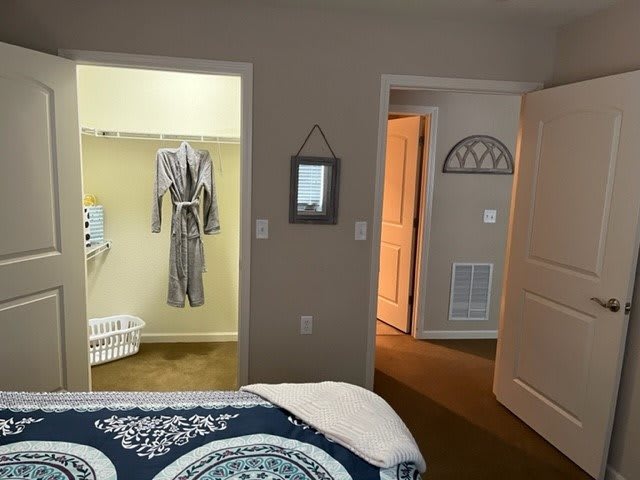 A cozy bedroom with an open closet and neatly arranged bedding.