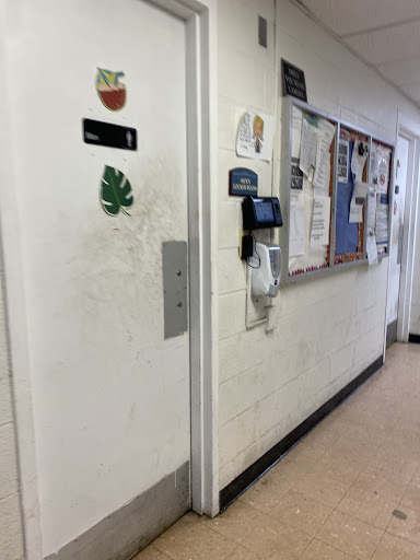 A hallway featuring a door with decorations and a bulletin board filled with various notices.