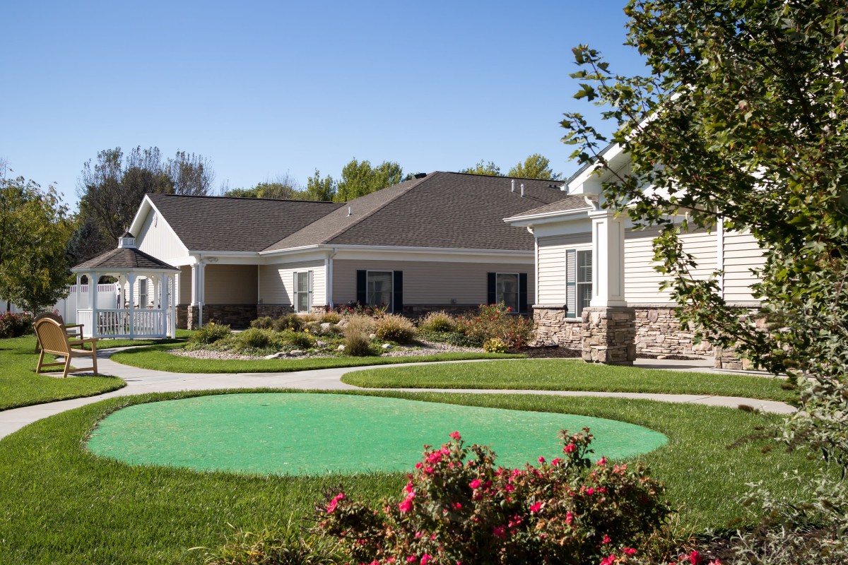 A scenic view of suburban houses with well-maintained lawns and gardens under a clear blue sky.