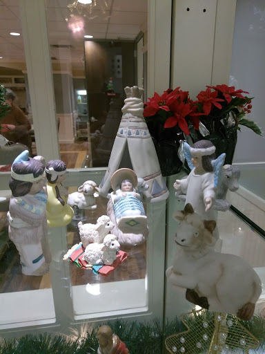 A beautifully arranged nativity scene featuring figurines, including angels and a manger, surrounded by festive poinsettias.
