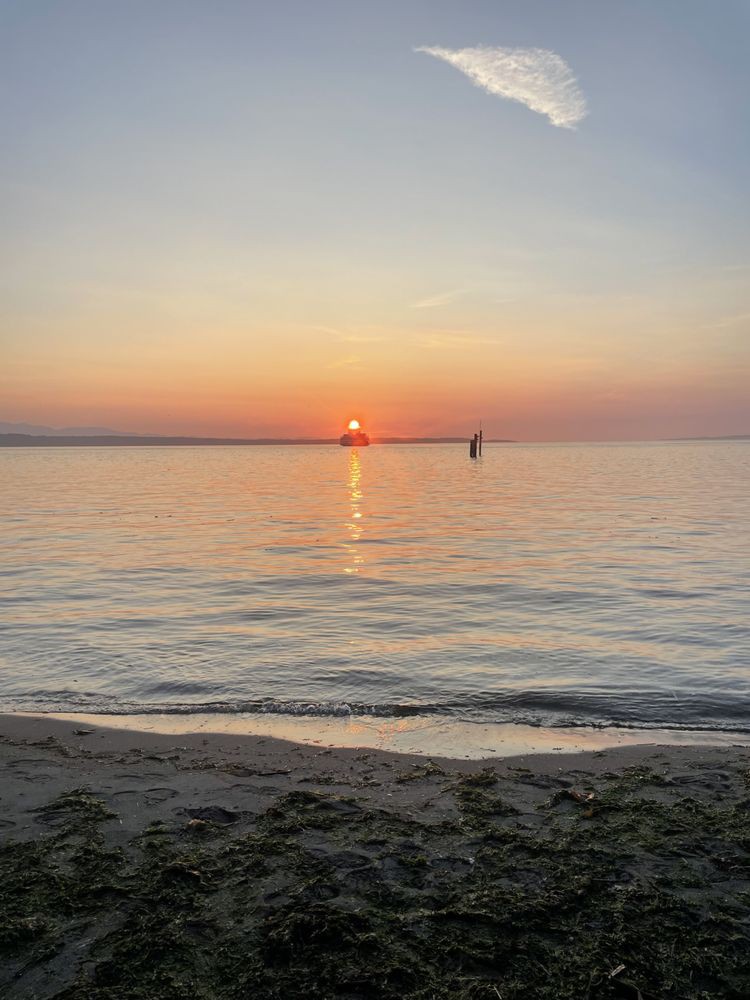 A serene sunset view over calm ocean waters with a distant silhouette.