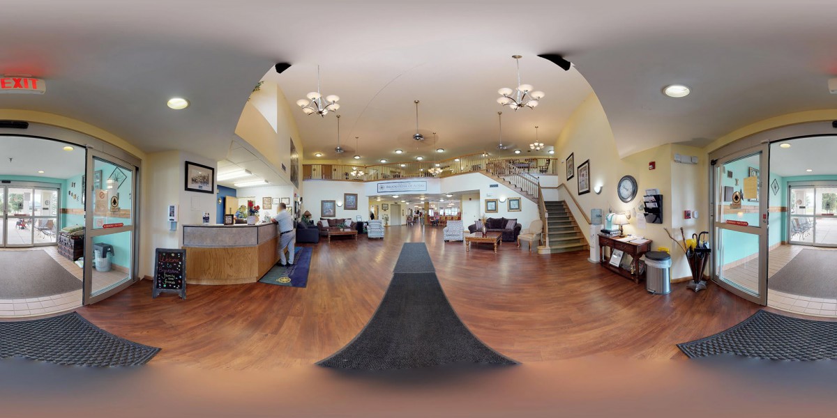 A spacious lobby area with a reception desk, seating, and large chandeliers.
