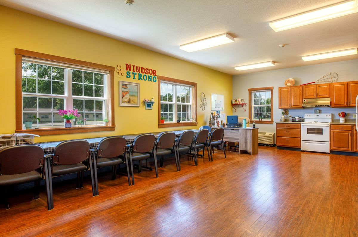 A bright waiting room with rows of chairs, large windows, and wooden flooring.