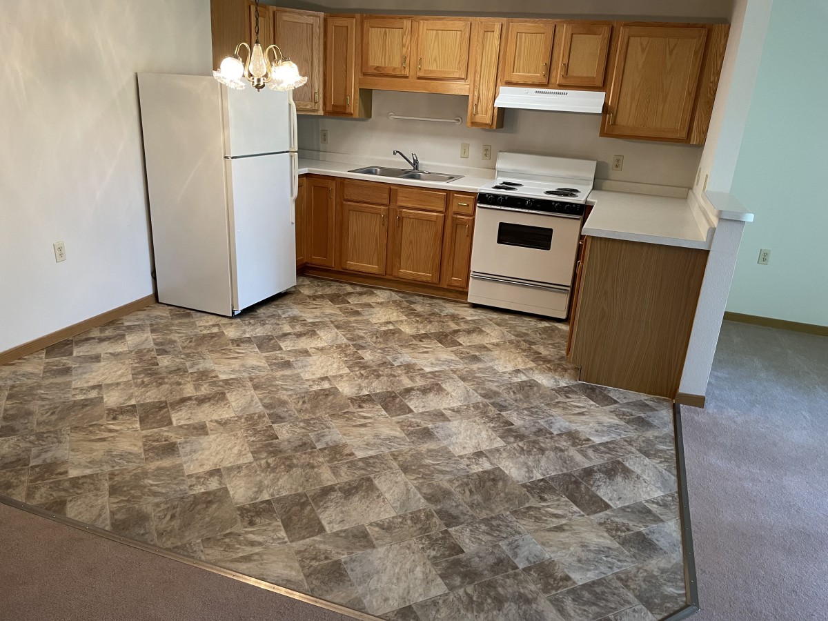 A compact kitchen with wooden cabinets, a white fridge, and stove.