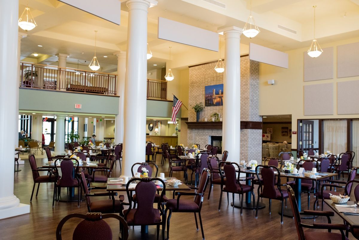 A spacious and elegantly designed dining area with multiple tables and chairs, featuring large columns and a warm atmosphere.