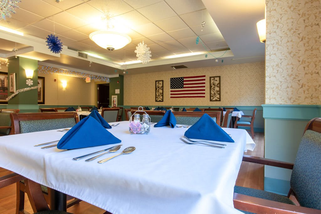 A neatly set table in a restaurant with an American flag on the wall.