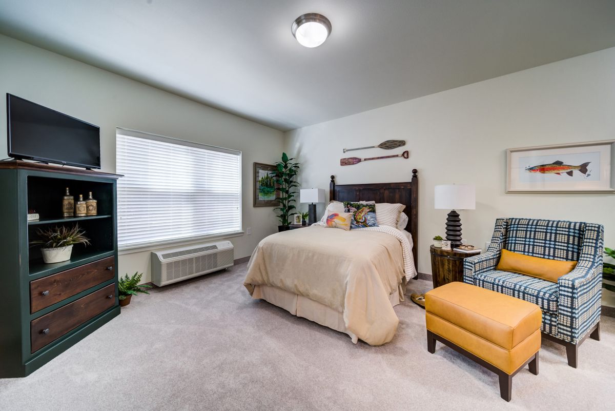 A cozy bedroom with a bed, armchair, and decorative elements.