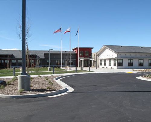 A school building with flags flying in front on a clear day.
