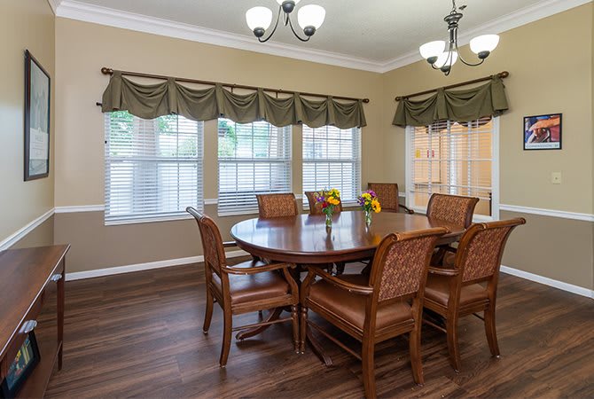 A well-appointed dining room featuring a wooden table, chairs, and elegant chandeliers.