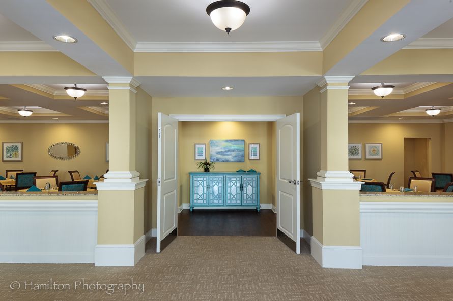 A well-lit lobby featuring a central blue cabinet, decorative artwork, and elegant pillars.