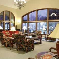 A cozy living room with large windows, comfortable seating, and warm lighting.
