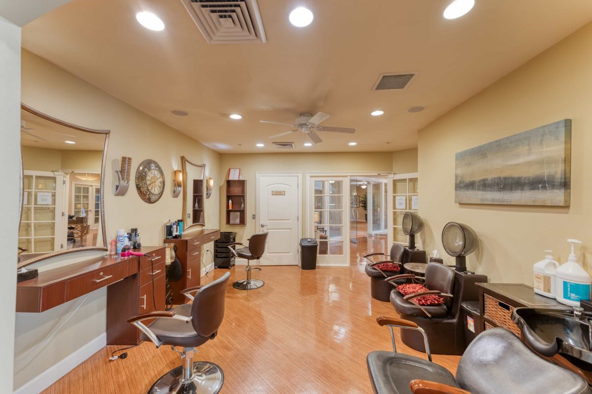 Interior view of a well-lit hair salon with chairs and mirrors arranged along the walls.