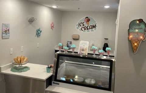 A cozy ice cream shop interior with a display case and colorful decorations.