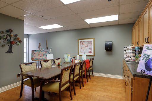 A spacious dining area featuring a long table with chairs, complemented by wall art and bright lighting.