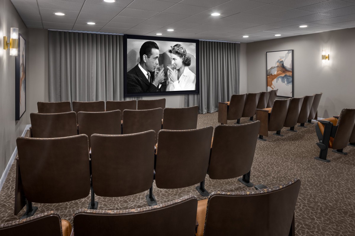 An empty theater room with a black and white movie playing on the screen.