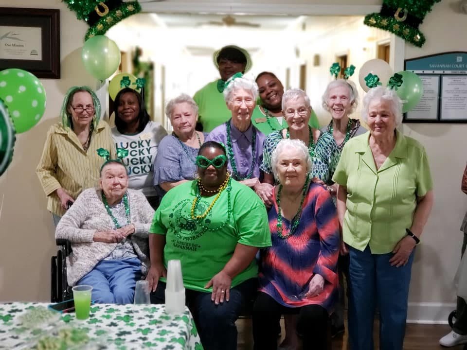 A joyful group of elderly individuals celebrating St. Patrick's Day with festive green attire and decorations.