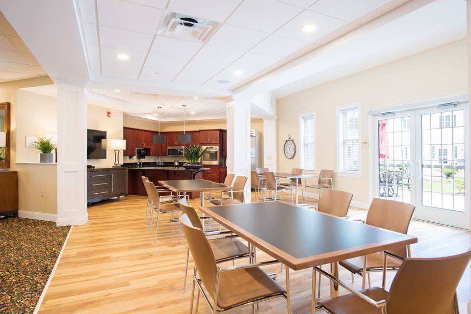 A modern dining area with a kitchen, featuring wooden floors and contemporary furniture.