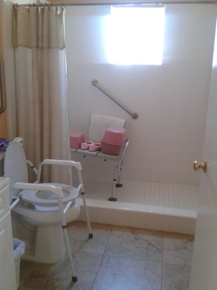 An accessible bathroom featuring a shower chair and grab bar for safety.