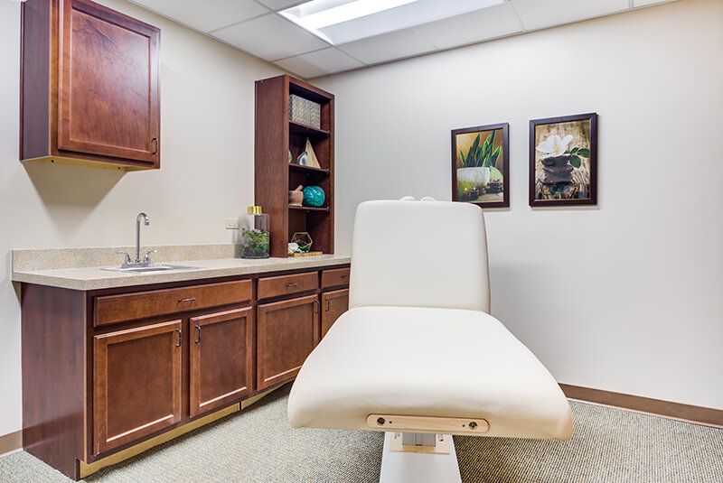 A clean and organized treatment room with an examination chair and cabinetry.
