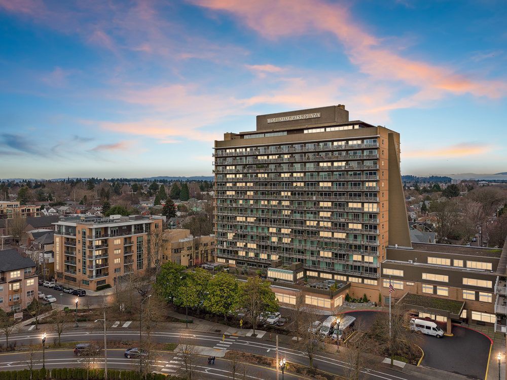 A high-rise building in an urban setting, captured under a colorful sunset sky.