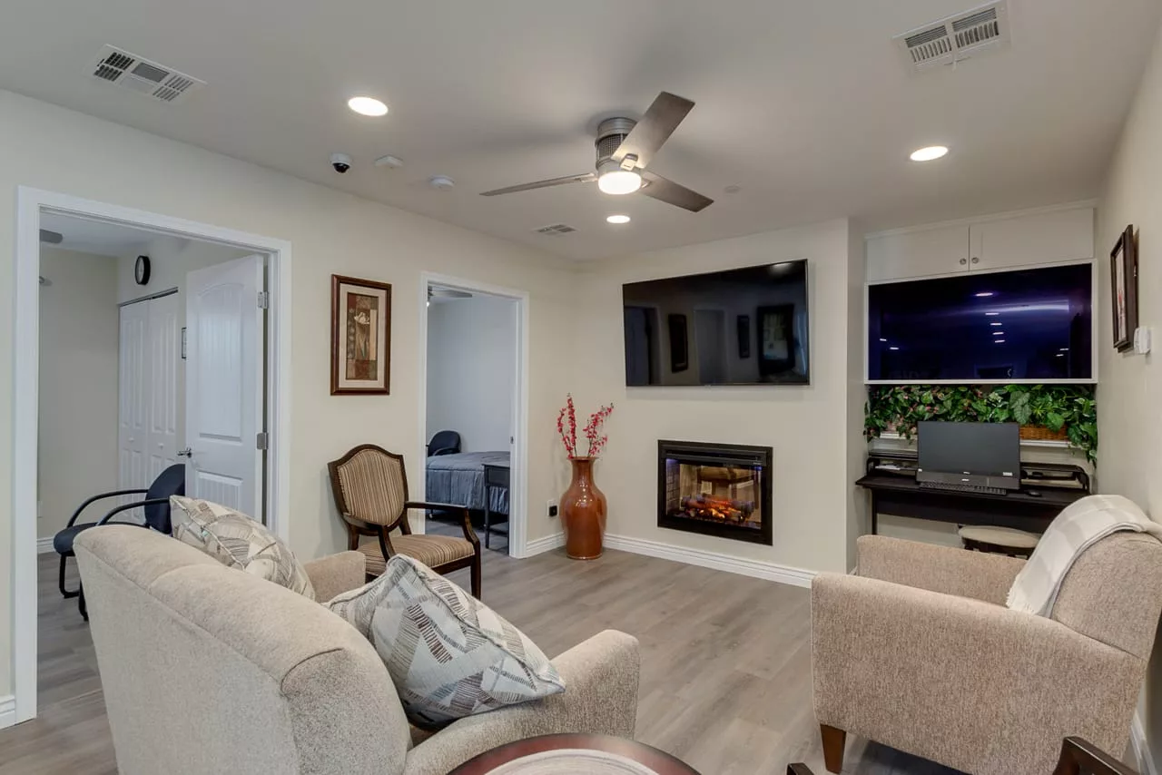 A modern living room featuring a cozy seating area, wall-mounted television, and an elegant fireplace.