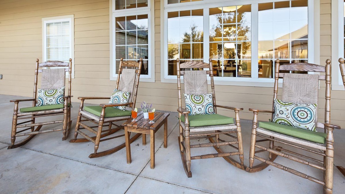A cozy porch setup with two rocking chairs, a small table, and drinks in front of large windows.