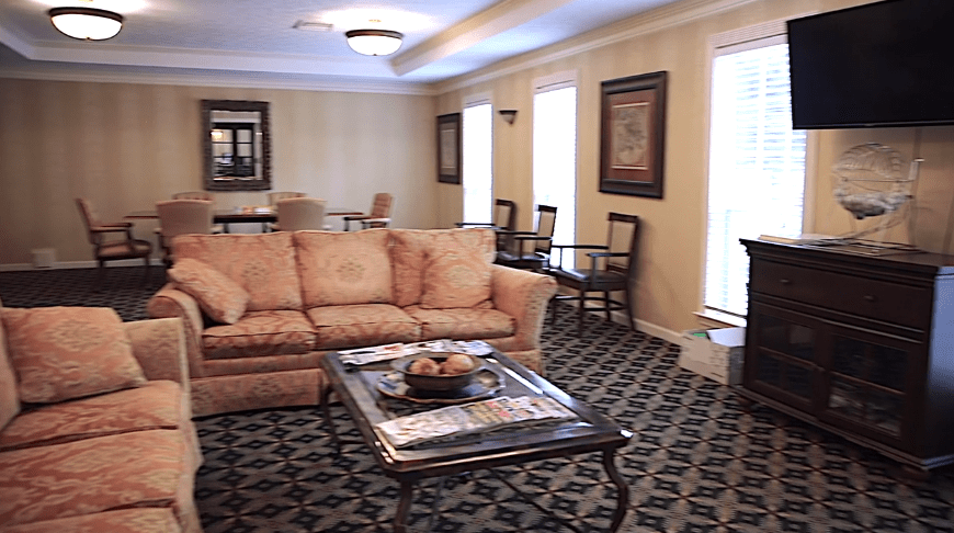 A cozy living room with a patterned carpet, elegant sofa, and a stylish coffee table, complemented by artwork on the walls.