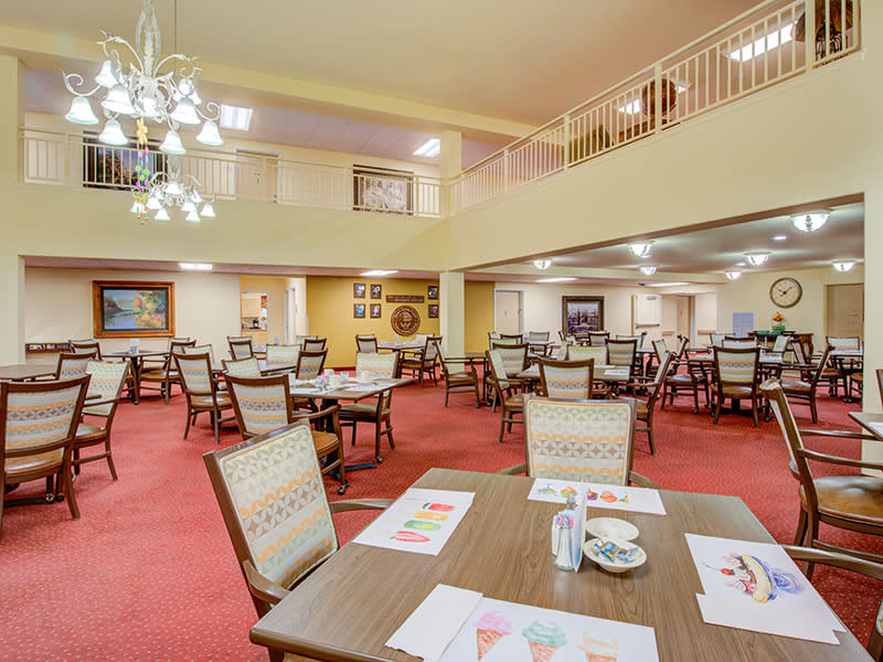 A spacious dining room with neatly arranged tables and chairs, featuring a warm and inviting decor.