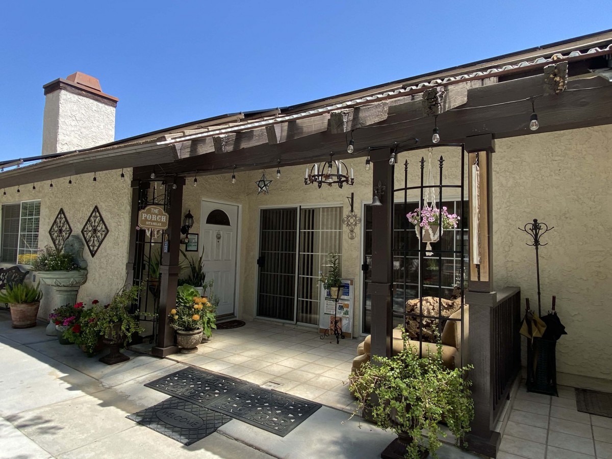 A residential house exterior featuring a pergola with plants surrounding the entrance.