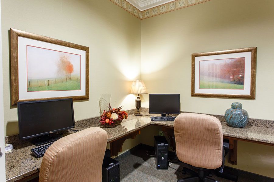A small office space with two desks, each equipped with a computer, surrounded by simple decor and artwork.