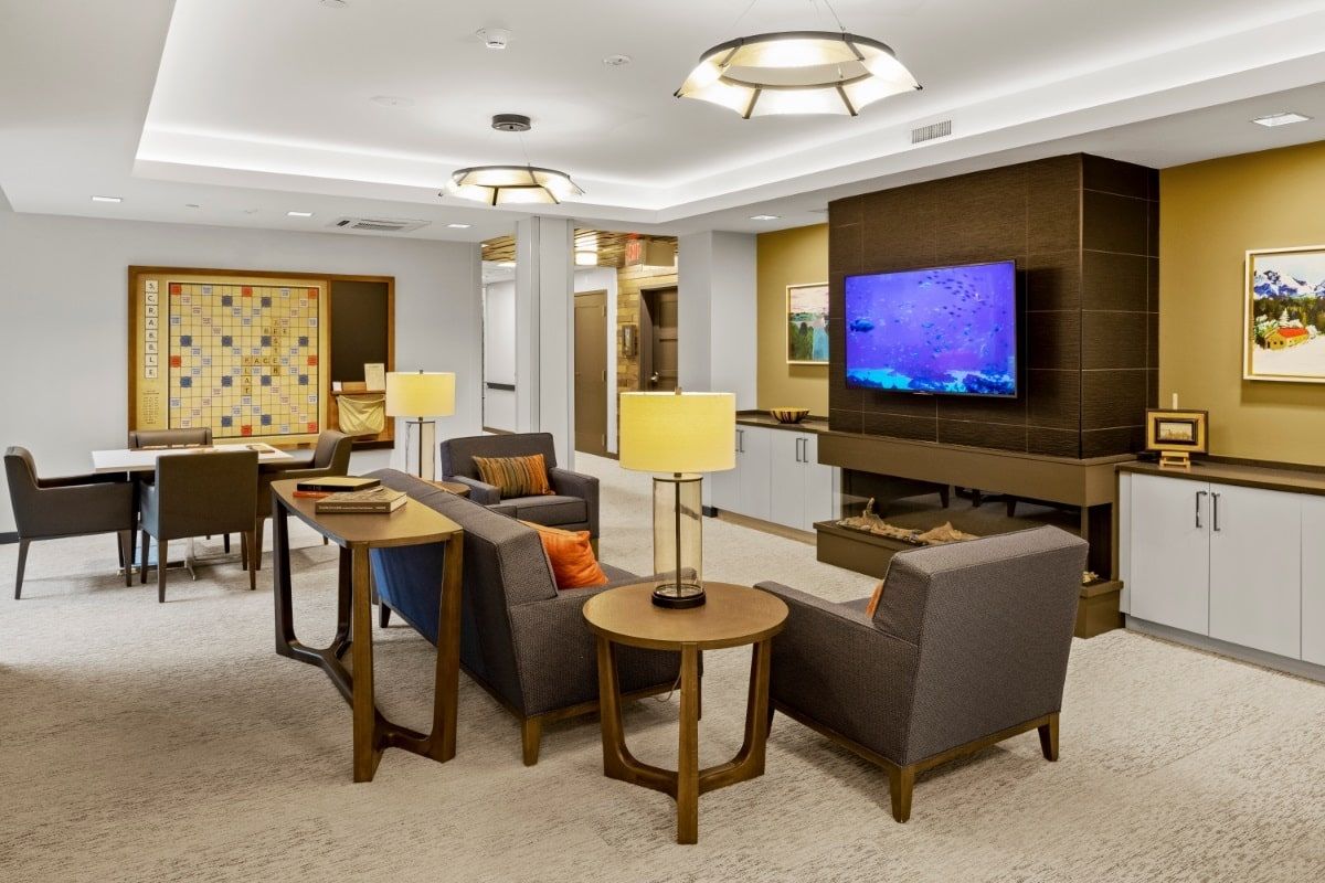 A modern lounge area featuring comfortable seating, a large TV, and elegant lighting.