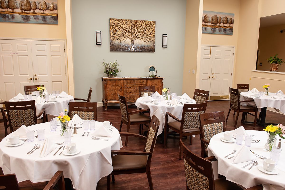 A cozy dining room with elegantly set tables and chairs, featuring tasteful decor.