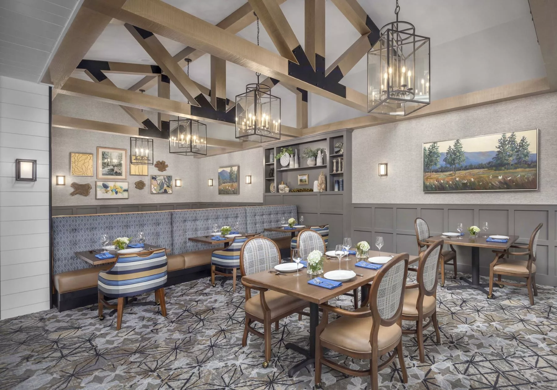 A beautifully designed restaurant dining area featuring elegant chandeliers, wooden beams, and stylish furnishings.