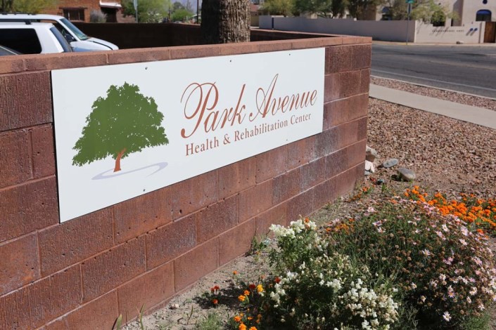 A sign for Park Avenue Health & Rehabilitation Center mounted on a brick wall with landscaping in the foreground.